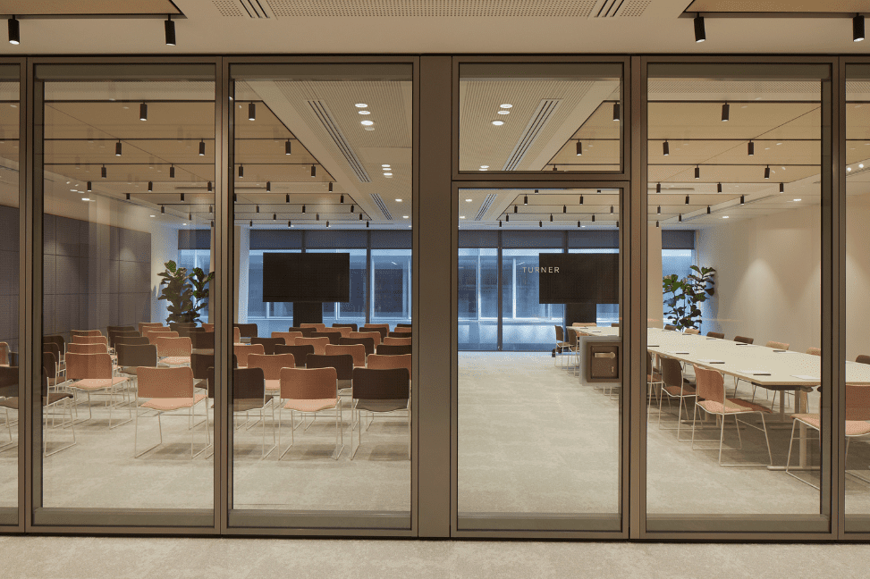 One of the meeting rooms in Myo St Paul's offices, converted to facilitate a presentation, with rows of audience seating and large screens.
